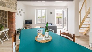 A dining area with a table set for two, a bottle of wine, and a basket of bread. - Family house near the beach (Saint-Marcouf)