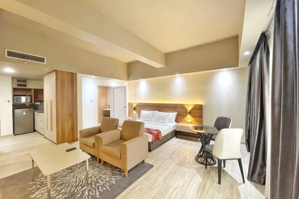 Une chambre d’hôtel équipée d’un lit, d’un bureau, d’une chaise, d’un canapé, d’une petite table et d’une kitchenette.
