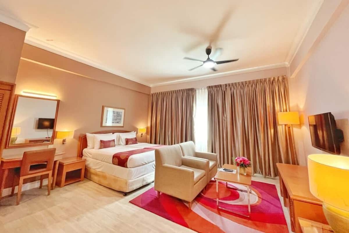 Une chambre d’hôtel équipée d’un lit, d’un canapé, d’un bureau, d’une chaise, d’une télévision et d’un ventilateur de plafond.