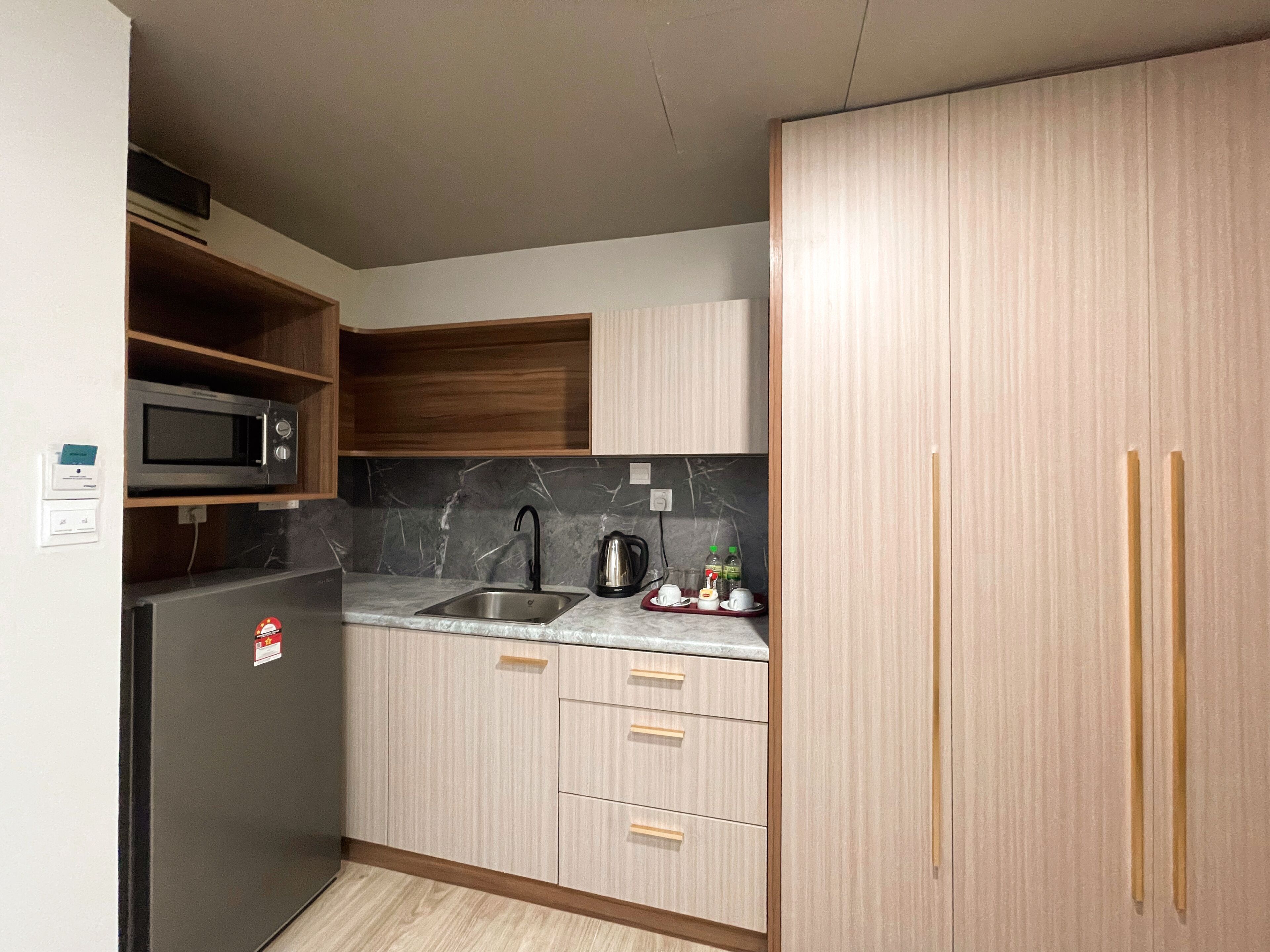 A compact kitchen with a built-in microwave, a sink, and wooden cabinets.