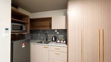 A compact kitchen with a built-in microwave, a sink, and wooden cabinets.