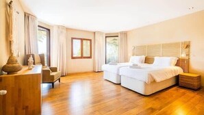 Ein modernes Hotelzimmer mit Holzboden, einem Bett mit weißen Bettwäsche, einem Schreibtisch mit einer Vase und einem Fenster mit Vorhängen.