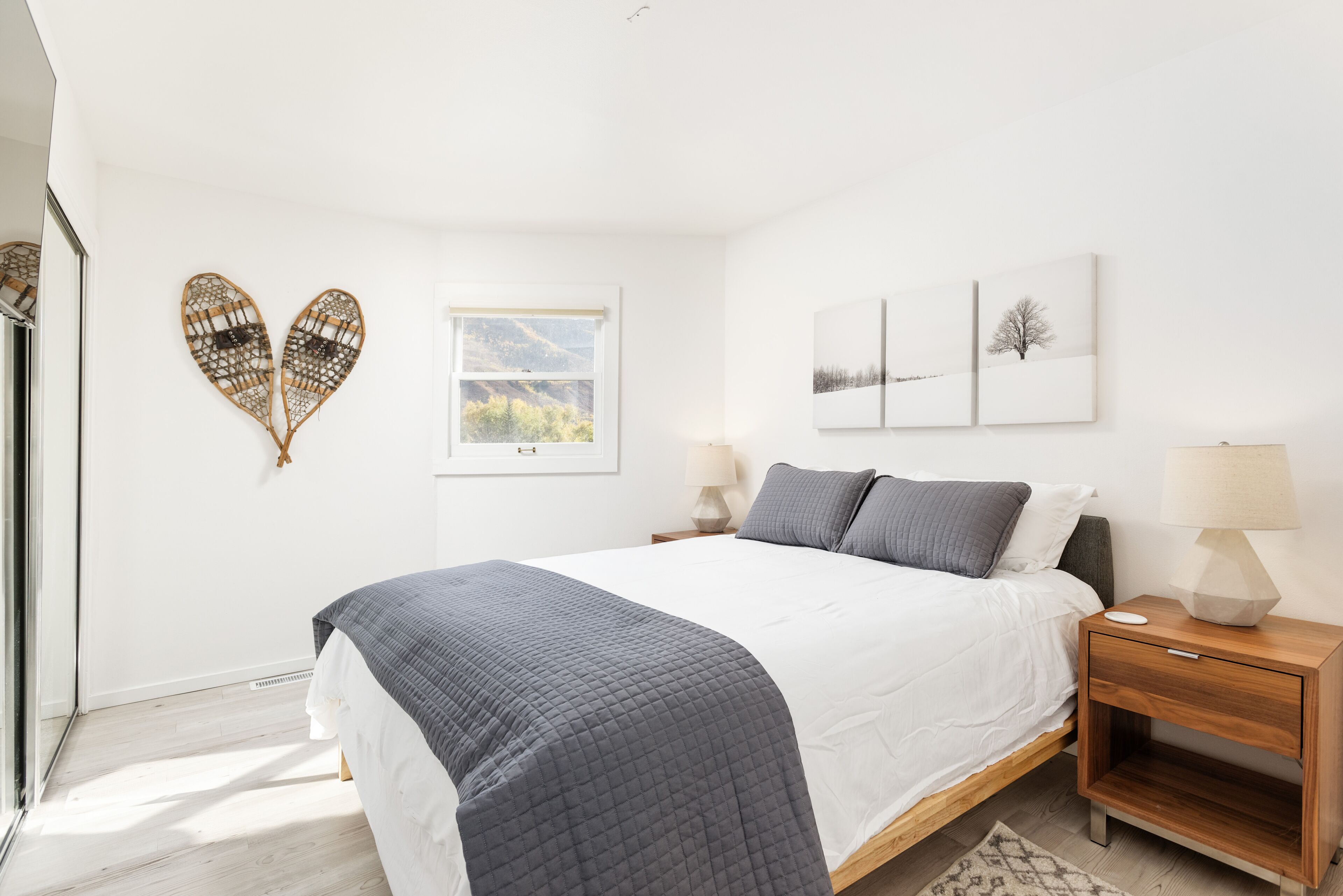 A bedroom with a bed, bedside tables, and wall art.