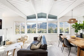 A spacious living room with a large window overlooking mountains, a wooden dining table, and a cozy seating area. - Aspen Ajax | Shadow Mountain #18 | 2B/2B (Aspen)