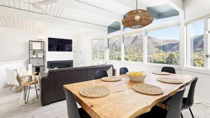 Een moderne keuken met een groot schiereiland, een eethoek met een houten tafel en uitzicht op bergen door grote ramen.