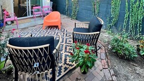 Eine Terrasse mit Gartenmöbeln, einem Backsteinboden und einer mit Kletterpflanzen bewachsenen Mauer.