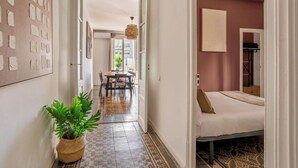 A hallway leading to a dining area and a bedroom with a bed and a nightstand. - Eixample / Gran Vía Historic Catalan 4 bedrooms (Barcelona)