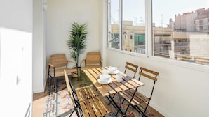 A balcony with a wooden table, chairs, and a potted plant. - Eixample / Gran Vía Historic Catalan 4 bedrooms (Barcelona)