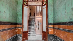 A grand hallway with a green wall and ornate ceiling, leading to a staircase. - Eixample / Gran Vía Historic Catalan 4 bedrooms (Barcelona)