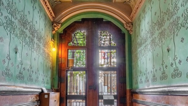 An ornate hallway with floral ceiling designs, a wooden door with glass panels, and a marble floor. - Eixample / Gran Vía Historic Catalan 4 bedrooms (Barcelona)