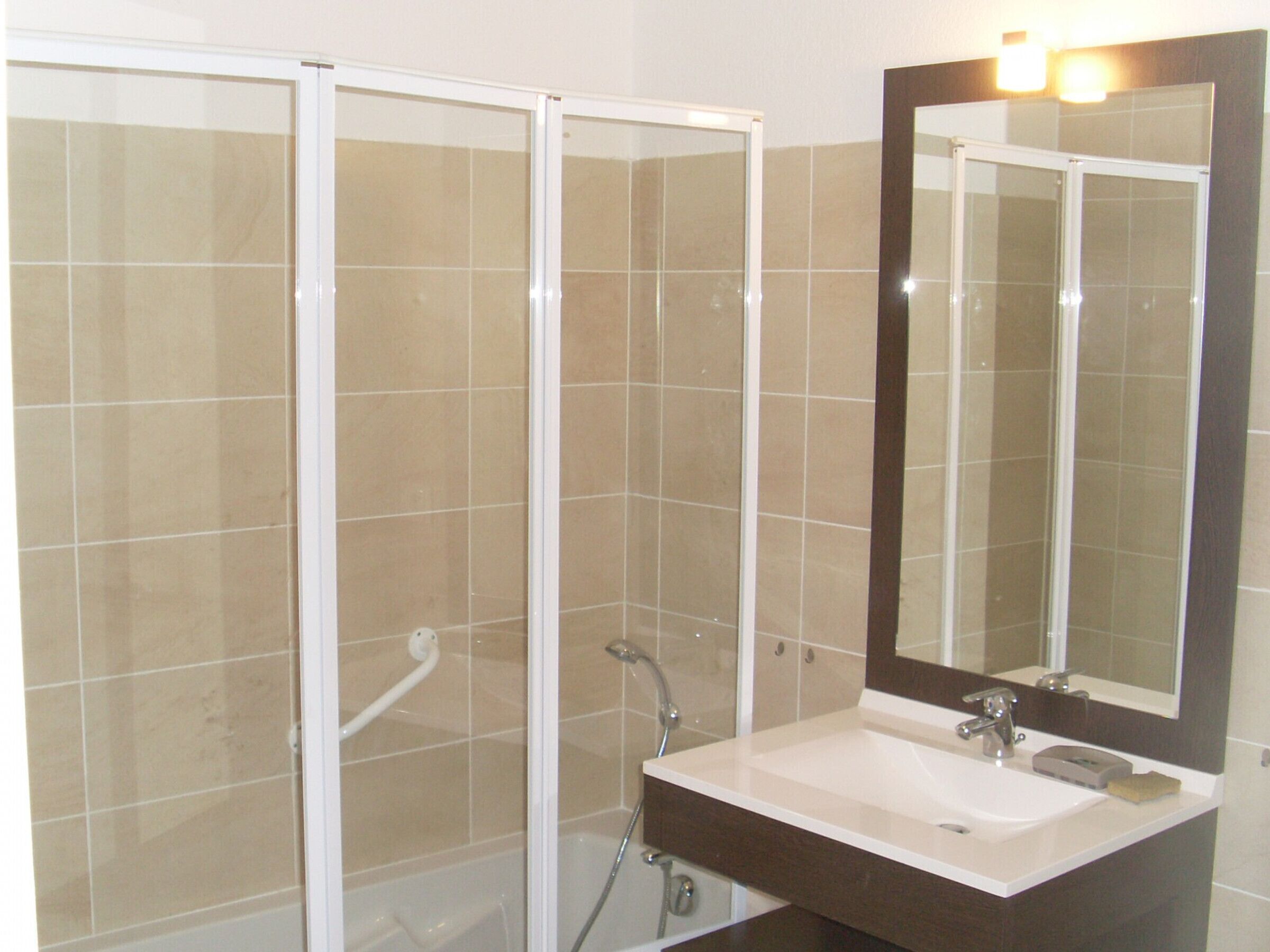 Une salle de bain avec une douche, un lavabo et un miroir.