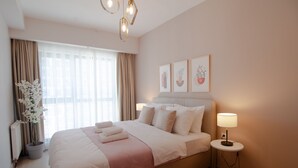 A hotel room with a large bed, bedside lamps, a potted plant, and artwork on the wall. - Cozy Retreat: Stylish 1BR Apt (Esenyurt)