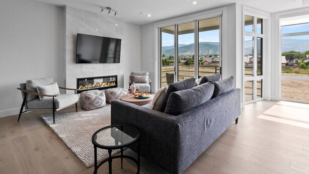 Ein modernes Wohnzimmer mit Kamin, bequemen Sitzmöglichkeiten und einem großen Fenster mit Blick auf die Landschaft.