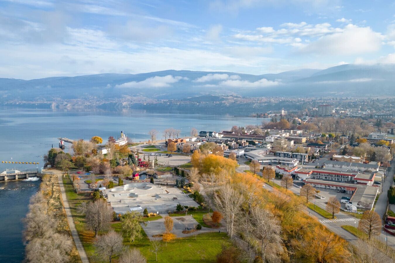 Een kuststadsgezicht met een jachthaven, gebouwen en uitzicht op zee en bergen.