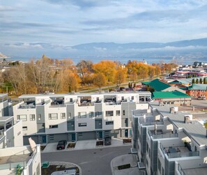 En modern, flervåningsbyggnad med en parkeringsplats och utsikt över en sjö och berg.