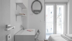 A modern hotel room with a white desk, a bed, and a large window with a view of buildings. - Lusso Bianco Nilie Hospitality MGMT (Thessaloniki)
