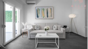 A modern living room with a white sofa, a coffee table, and a painting on the wall. - Lusso Bianco Nilie Hospitality MGMT (Thessaloniki)