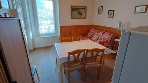 Un comedor con mesa y sillas, techo de madera y ventana con vistas.