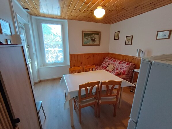 Un espace repas comprenant une table et des chaises, un plafond en bois et une fenêtre donnant sur un paysage agréable.
