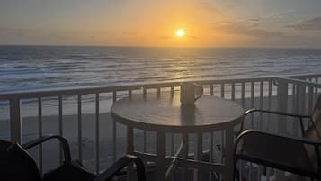 Uitzicht op zee, met een tafel en stoelen, een hekwerk en een mok op tafel.