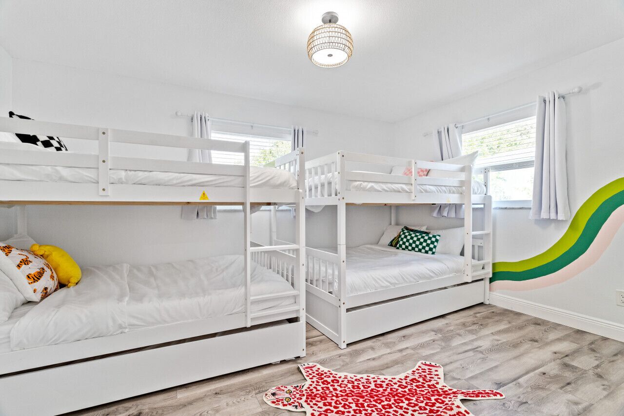 Una habitación con literas, una lámpara en el techo y una ventana con cortinas.
