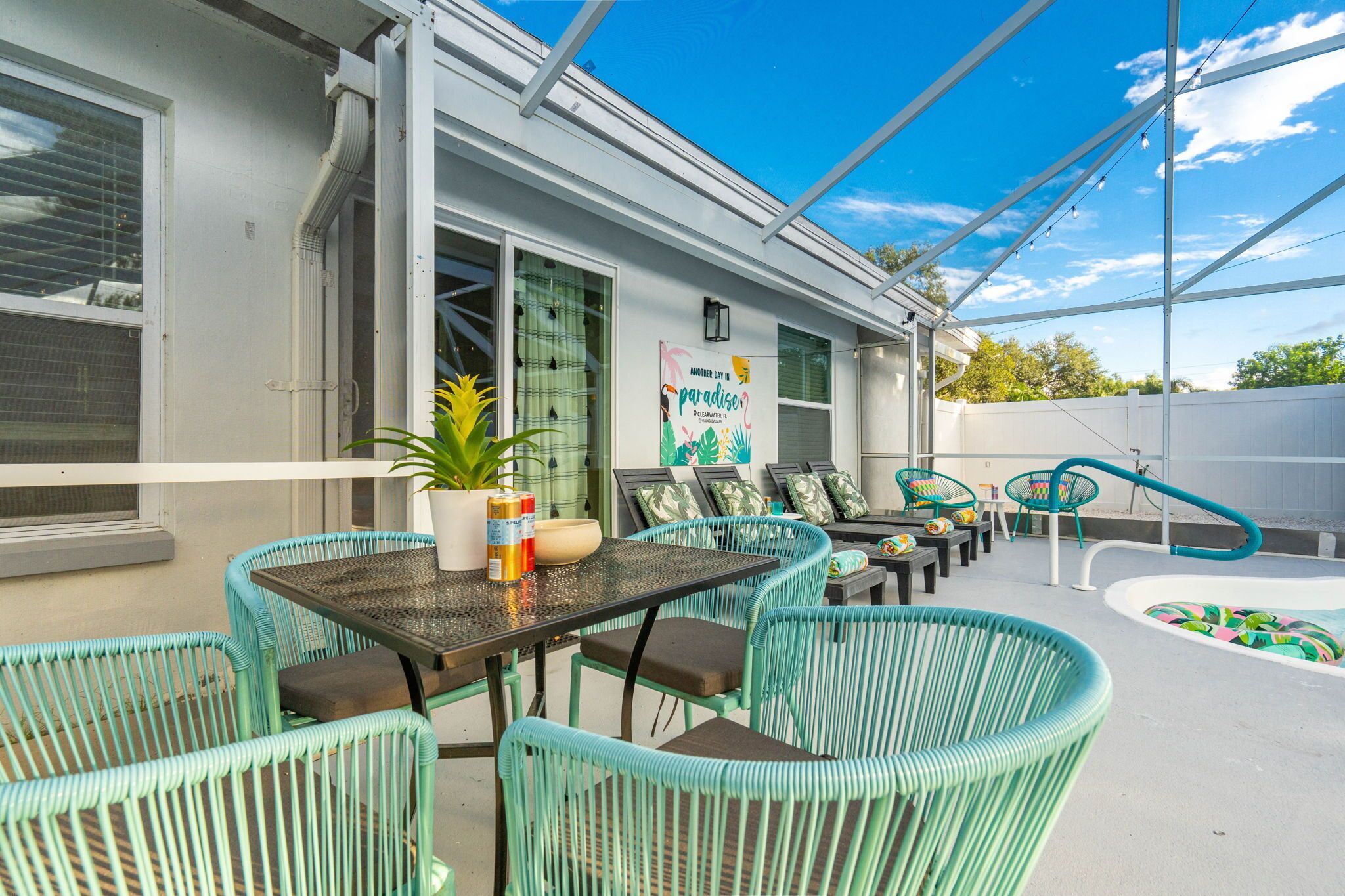 An outdoor patio with a table and chairs, a pool, and a sign advertising a paradise.