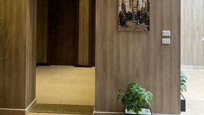 A modern lobby with wooden paneling, a framed artwork depicting a historical scene, and a potted plant. - Rotana Palace Suites (Cairo)
