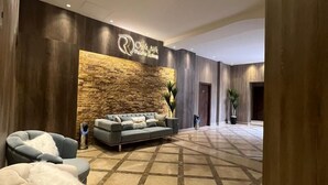 A modern lobby with a stone accent wall, a reception desk, a sofa, and a seating area. - Rotana Palace Suites (Cairo)