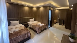 A modern hotel room with two beds, a small seating area, and a view of the city. - Rotana Palace Suites (Cairo)