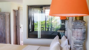 A hotel room with a bed, a window with a view of greenery, and a wooden wardrobe. - Naomi Beach Resort (Weligama)