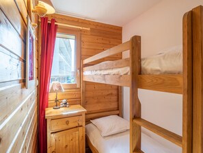 A bunk bed room with wooden walls, a window with red curtains, a bedside table with a lamp, and a teddy bear. - Central apartment, pets allowed, near ski slopes (Huez)
