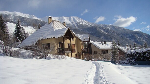 Une maison recouverte de neige, avec une montagne en toile de fond.