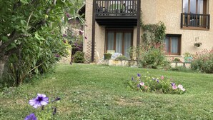 Une maison avec un balcon, un jardin fleuri et une pelouse.