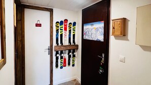 Un pasillo con una puerta que da a una habitación, un esquí con esquíes, un mapa de esquí y un armario.