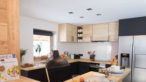 Eine moderne Küche mit Holzschränken, einem eingebauten Herd und einem Edelstahlkühlschrank.
