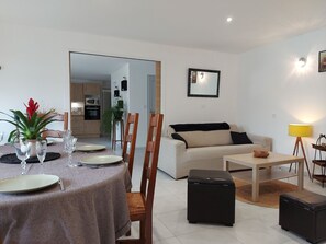 A modern living room with a dining area, a sofa, a coffee table, and a lamp.
