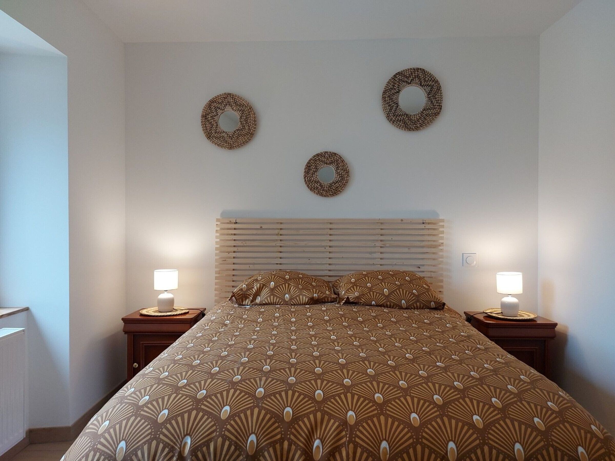 A bedroom with a bed, two bedside lamps, and three wall-mounted circular decorations.