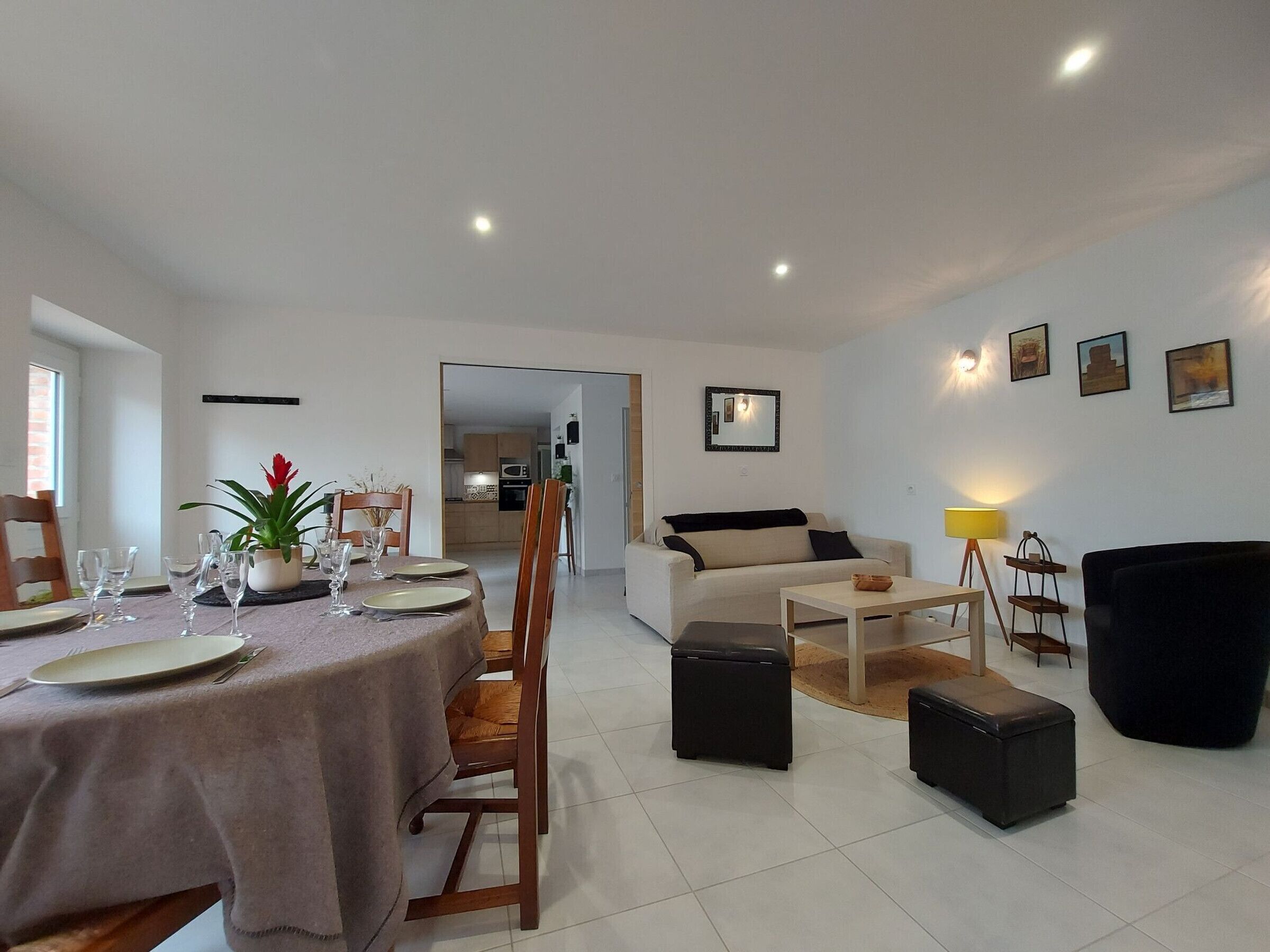 A modern living room with a dining area, a sofa, and a coffee table. There is a kitchen in the background.