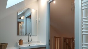 Une salle de bain moderne avec un lavabo blanc, un meuble-lavabo en bois et un miroir au-dessus.