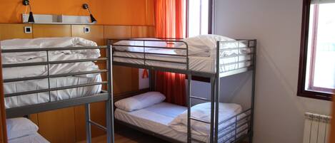 Une chambre avec des lits superposés, un plancher en bois et des murs orange.