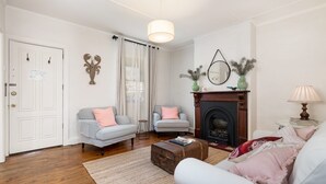 Una sala de estar con chimenea, dos sofás, un tapete y piso de madera.