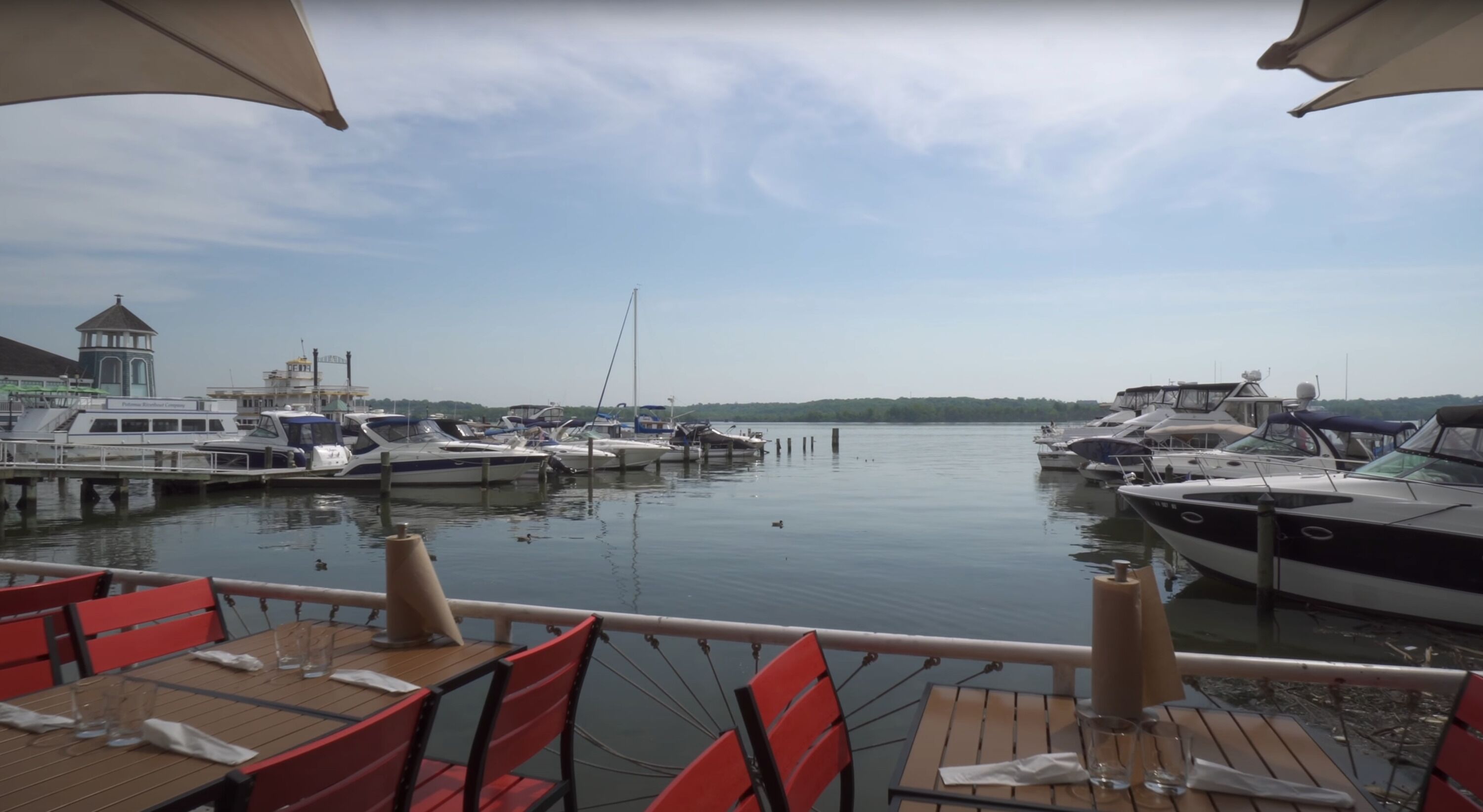 A marina with boats docked, a small building, and a table with chairs for dining.