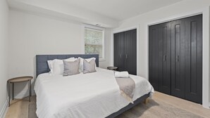 A bedroom with a bed, bedside tables, a window with blinds, and a wardrobe. - West Taylor Run Hotel (Alexandria)