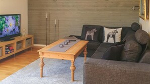 A living room with a wooden coffee table, grey sofa, and a television on a wooden stand. - 3 bedroom awesome home in Malungsfors (Malungsfors)