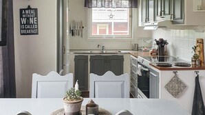 A kitchen with white cabinets, a dining table with chairs, and a window with a view of a house. - 3 bedroom awesome home in Malungsfors (Malungsfors)