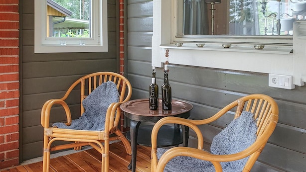 Two wicker chairs with blue cushions, a small round table, and two bottles on a window sill. - 3 bedroom awesome home in Malungsfors (Malungsfors)