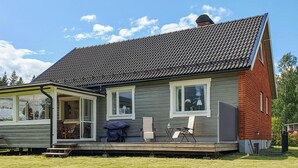 A house with a grey exterior, a dark tiled roof, and a wooden porch with outdoor furniture. - 3 bedroom awesome home in Malungsfors (Malungsfors)