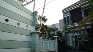 Ett avgränsat bostadsområde med en ljusblå yttervägg, en dekorativ grind och en krukväxt med röda blommor.