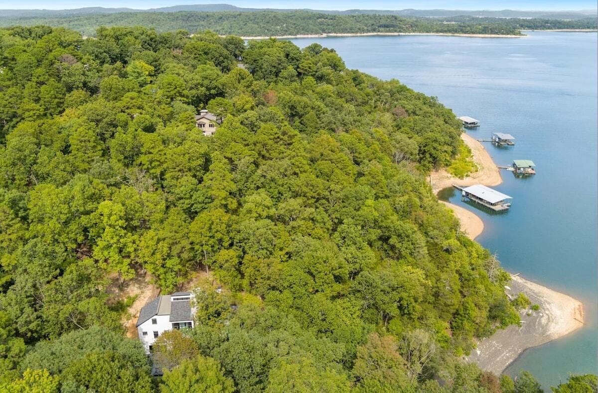 Una casa apartada rodeada de un bosque frondoso, un muelle y un lago tranquilo.