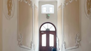 A hallway with ornate wall decorations, a central light fixture, and a door at the end.